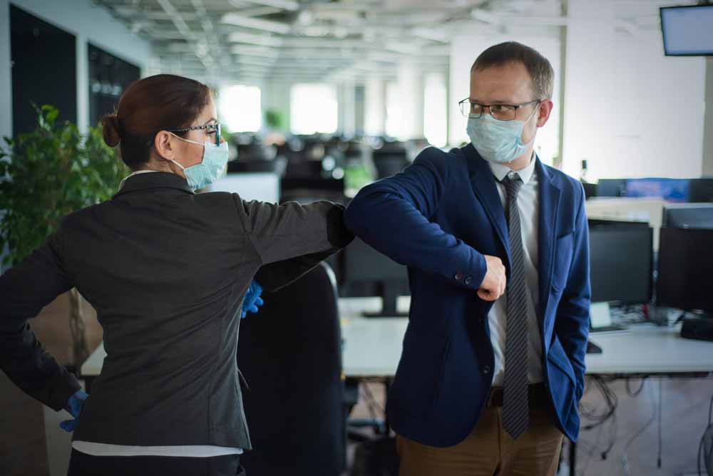 Photo of two office workers bumping elbows.